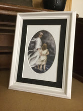 Load image into Gallery viewer, A small white framed version of the black 5 inch by 7 inch black and white oval matted version of the print of Jesus and little child walking on the water together in a bad storm. A matted print illustrated by artist Suzanne Davis Harden. This small frame does not include glass.