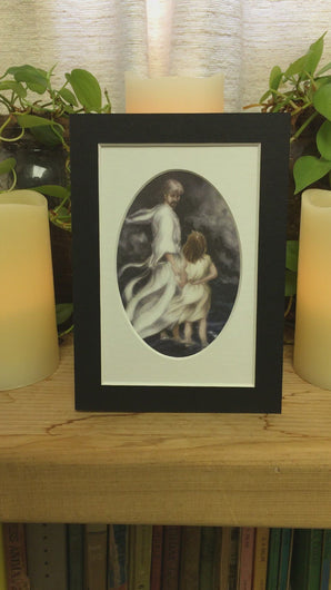 A video of the small 5 inch by 7 inch print of Jesus and little child walking on the water together in a bad storm.  A  matted print illustrated by artist Suzanne Davis Harden. The matted print is black with a white interior and oval opening.